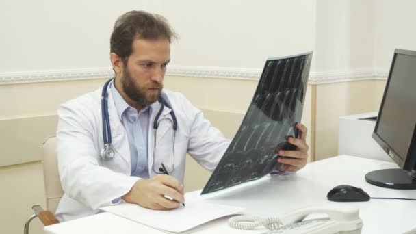El médico está escribiendo una recomendación después de revisar la radiografía. — Vídeos de Stock