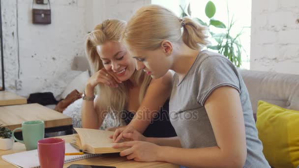 Две девушки читают книгу — стоковое видео