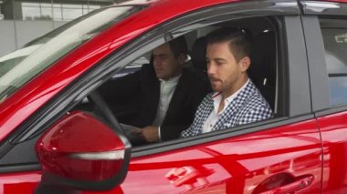 Satıcı ve alıcı yeni arabanın içinde oturuyorlar