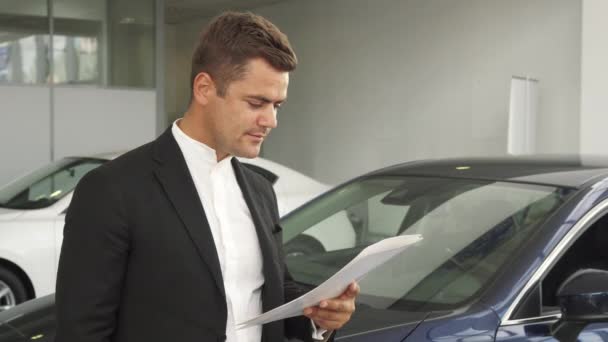 En nöjd köpare läser dokument av bilen — Stockvideo