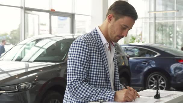 Un acheteur attentif signe un contrat pour l'achat d'une voiture — Video