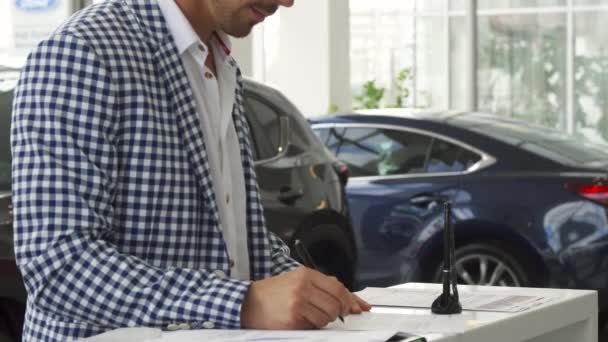 Серьезный покупатель подписывает документы на покупку автомобиля — стоковое видео