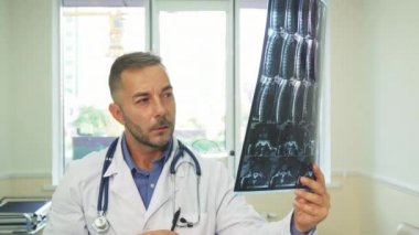 Düşünceli bir doktor dikkatlice bir röntgen çekim inceliyor