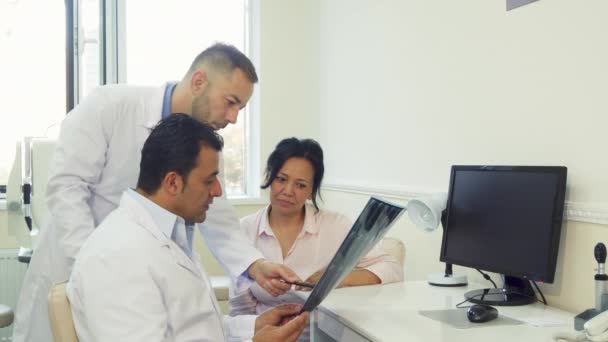 Ervaren artsen vertellen de patiënt de resultaten van een röntgenfoto — Stockvideo