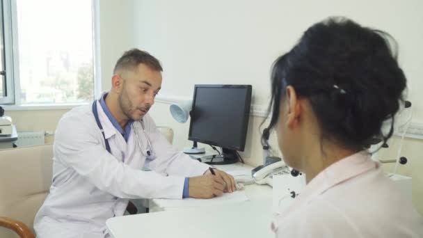 Un médico tranquilo escribe un certificado médico a su cliente — Vídeo de stock