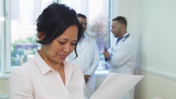 Una paciente feliz está estudiando los resultados de su examen médico. — Vídeo de stock