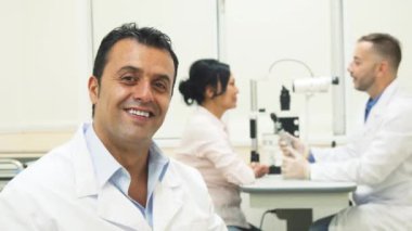 Doktor gözlük koyar ve arka plan üzerinde başka bir doktor hasta incelerken başparmak ortaya