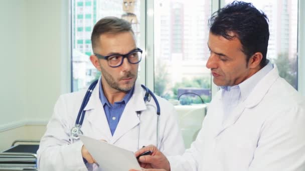 Dos doctores experimentados leen el certificado médico de los pacientes — Vídeos de Stock