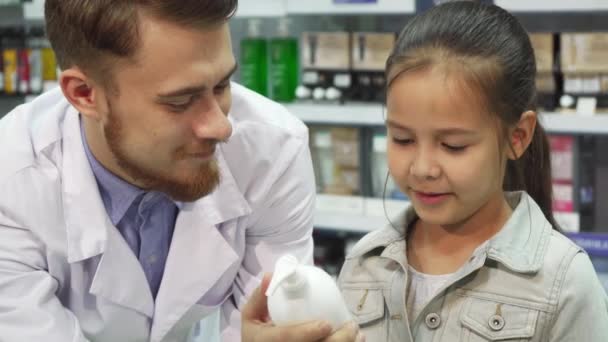 Ein junger Kunde wählt mit Hilfe einer Apotheke aus, welches Produkt er kaufen möchte — Stockvideo