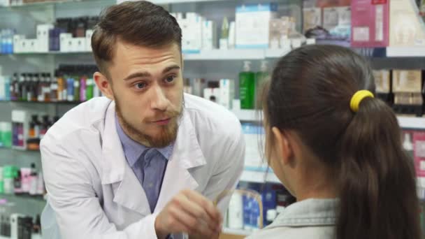 Schöne Apothekerin schenkt dem kleinen Mädchen ihre Einkäufe — Stockvideo