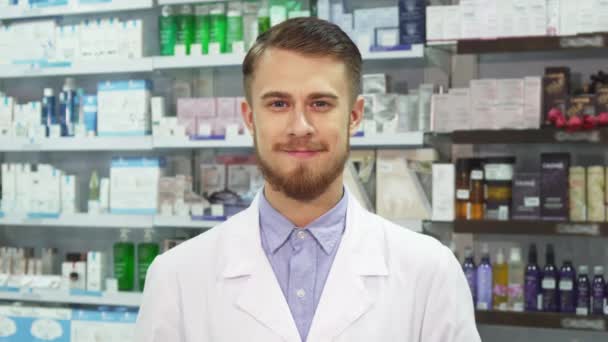 Joven farmacéutico mostrando medicación y sonriendo — Vídeo de stock