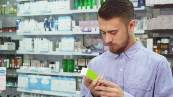 Een jonge man een geneeskunde houdt in zijn hand en leest iets op de telefoon — Stockvideo