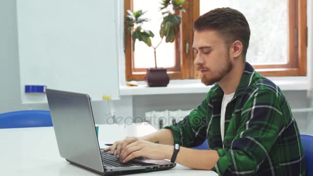 Un joven está sentado frente a una computadora en una institución educativa — Vídeos de Stock