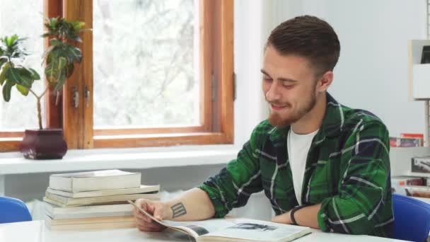 Un chico lindo se ríe de lo que leyó en el libro — Vídeos de Stock