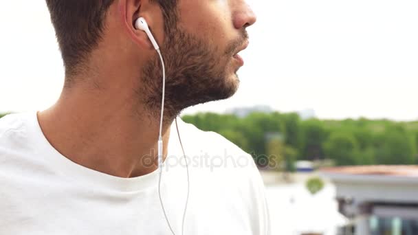 Un joven hace un sonido en sus auriculares más fuerte — Vídeos de Stock