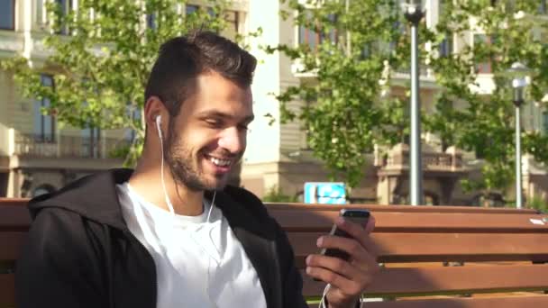 Um cara alegre atende uma chamada de vídeo no telefone — Vídeo de Stock