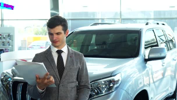 Un comprador feliz presenta un coche de la sala de exposición de automóviles — Vídeo de stock