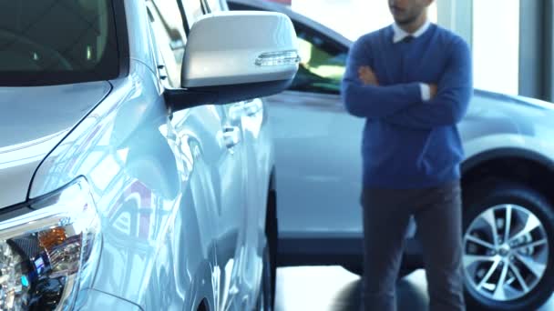 Um homem sólido caminha pelo showroom do automóvel e olha para o carro — Vídeo de Stock