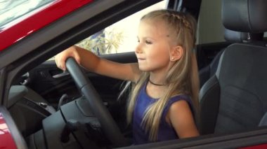 Güzel sevimli kız bir otomobilin direksiyon simidi döner