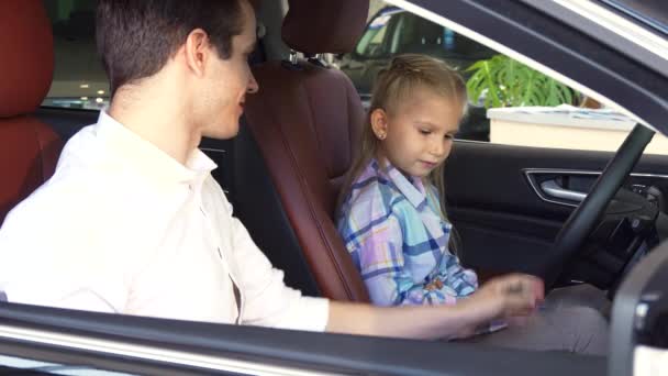 Маленькая девочка сидит за рулем новой машины — стоковое видео