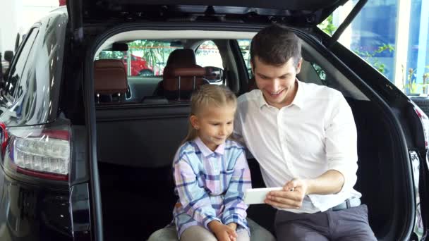 Um jovem pai com uma filha faz selfie no fundo de um carro — Vídeo de Stock