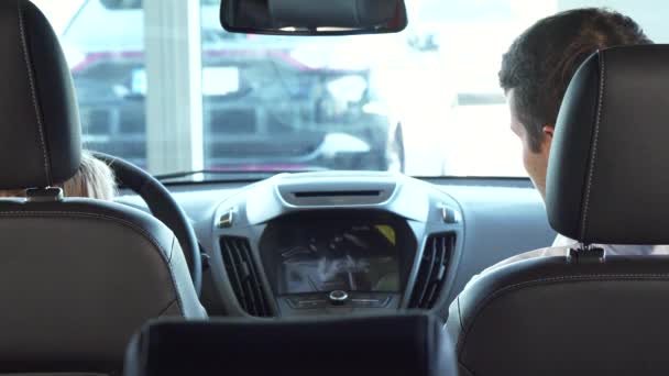 O pai engraçado com sua filha senta-se nos assentos dianteiros e olha a tela pequena do carro — Vídeo de Stock