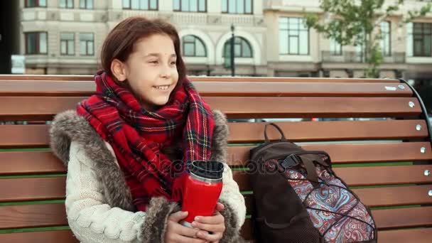 Küçük bir kız büyük bir şehirde bir bankta oturuyor — Stok video