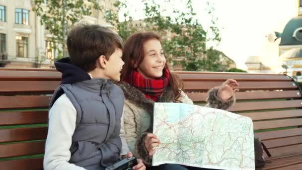 Los jóvenes se sientan en un banco y toman fotos de lugares de interés — Vídeo de stock