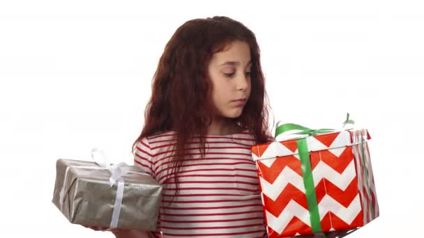 Una niña reflexiva mira sus dos regalos y elige entre ellos — Vídeo de stock