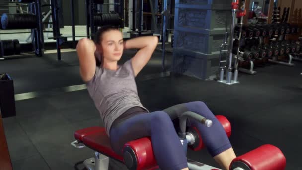 Молодая девушка выполняет упражнения с прессой на специальном тренажере — стоковое видео