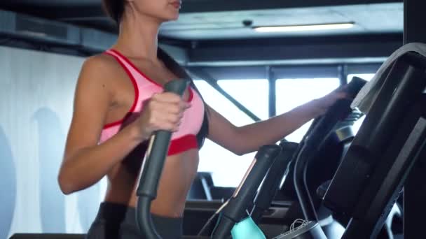 Спортивная девушка делает упражнения на специальном эллипсоидном тренажере — стоковое видео