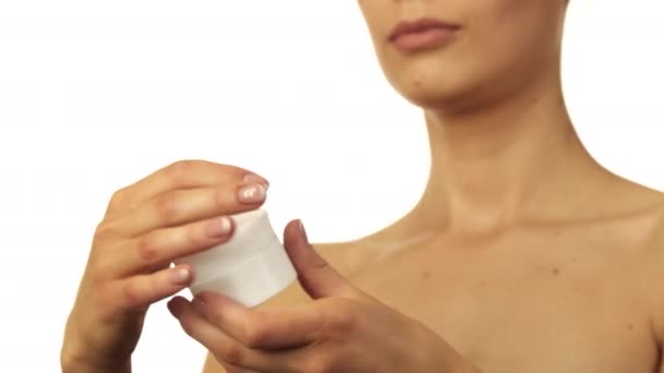 Het mooie meisje opent een pot van crème en zet het op haar vinger — Stockvideo