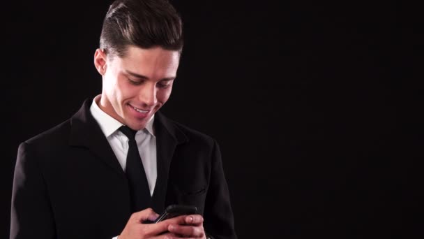 Ένας χαμογελαστός άνθρωπος σε ένα κοστούμι κάτι πληκτρολογώντας το τηλέφωνό του — Αρχείο Βίντεο