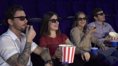 İki çiftler sinemada oturup patlamış mısır yemek