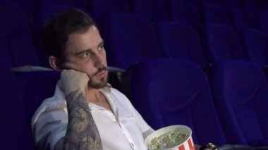 Genç bir adam bir filmde oturur ve uykuya dalar
