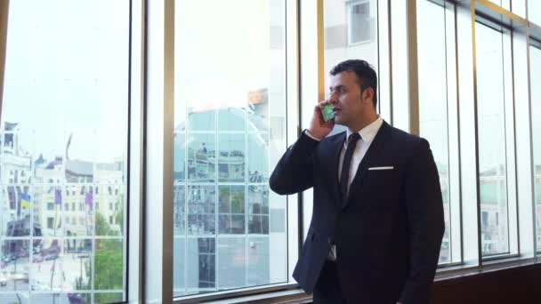 Hombre de negocios toma una llamada telefónica y mira su reloj de pulsera — Vídeos de Stock