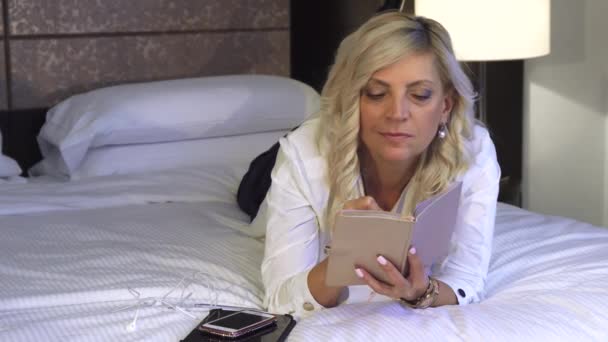 Mujer de negocios está acostada en el sofá y escribiendo en un cuaderno — Vídeos de Stock