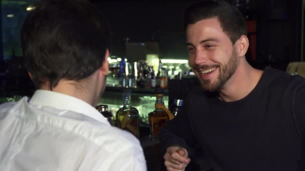 Jóvenes amigos masculinos hablando mientras toman bebidas juntos en el bar — Vídeos de Stock