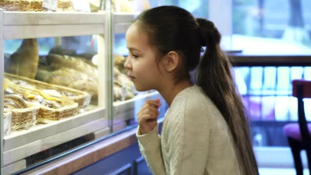 Linda niña mirando la exhibición en la panadería local — Vídeos de Stock
