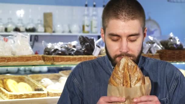 Primer plano de un hombre alegre oliendo pan recién horneado — Vídeos de Stock
