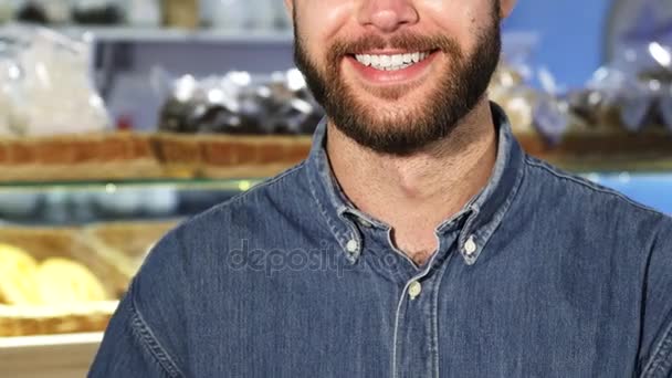 Recortado de cerca f un hombre barbudo sonriendo sosteniendo una barra de pan fresco — Vídeos de Stock