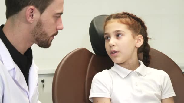 Uma menina triste descreve sua dor de dente para o médico — Vídeo de Stock