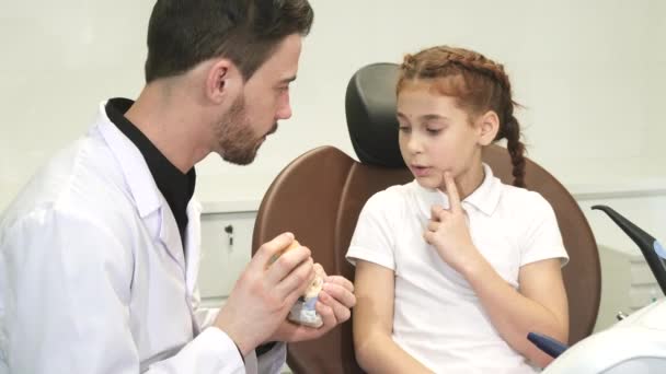 Розумний лікар розповідає маленькій дівчинці про будову щелепи людини — стокове відео