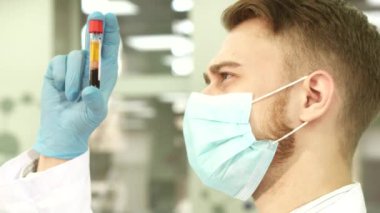 Deneyimli laboratuvar asistanı dikkatle bir tüp kan ile inceler