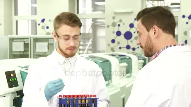 Collega's in het laboratorium bespreken de resultaten van hun activiteiten — Stockvideo