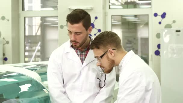 Двоє молодих асистентів лабораторії обговорюють нюанси їх робочого процесу — стокове відео
