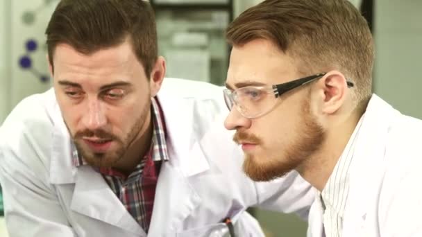 Közeli kép: a laboratóriumi technikusok, akik komoly beszélgetést folytasson arcai — Stock videók