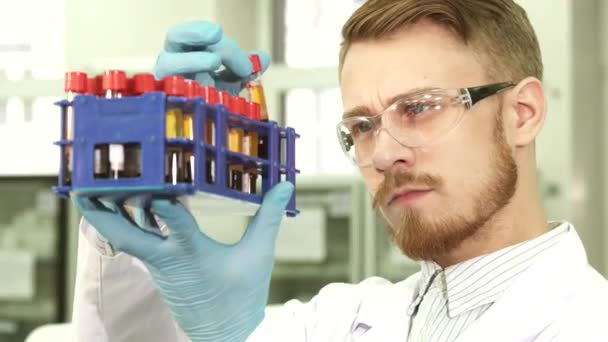 A serious laboratory assistant carefully examines each tube individually — Stock Video