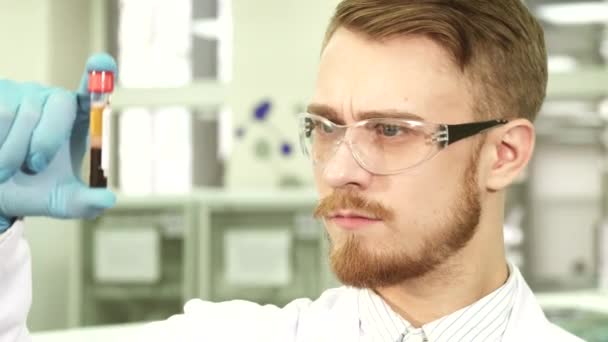 Gros plan du visage du travailleur de laboratoire qui étudie l'éprouvette avec les essais — Video
