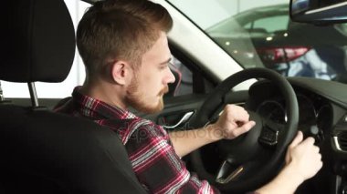 Yeni bir arabada oturan omzunun üzerinden kameraya gülümseyen çekici sakallı adam